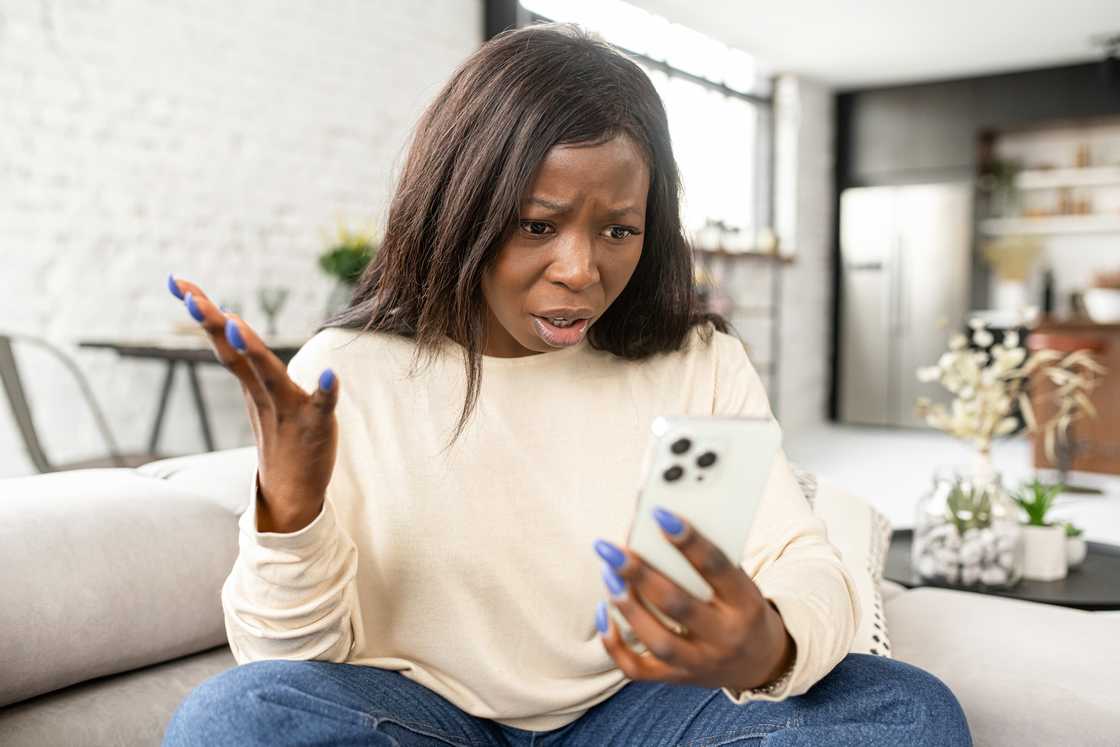 Novels Black woman shocked while staring at her phone.