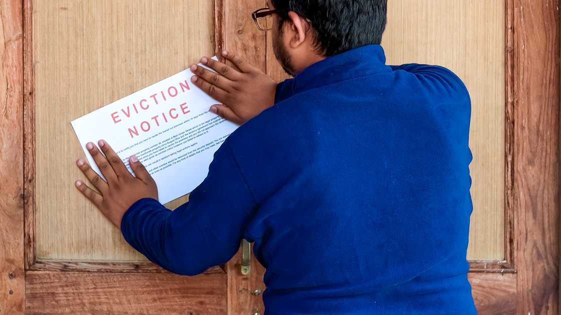 A man sticking an eviction notice on the door.