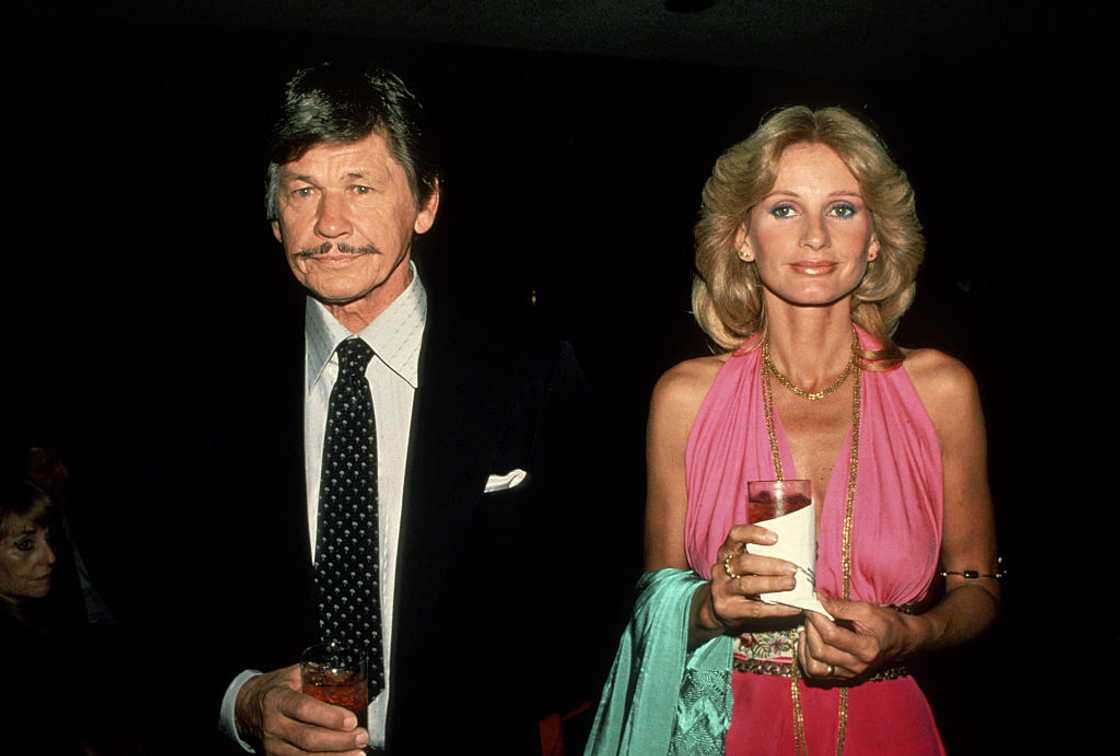 Charles Bronson and Jill Ireland posing for a photo holding a drink in a glass Charles Bronson and Jill Ireland posing for a photo holding a drink in a glass