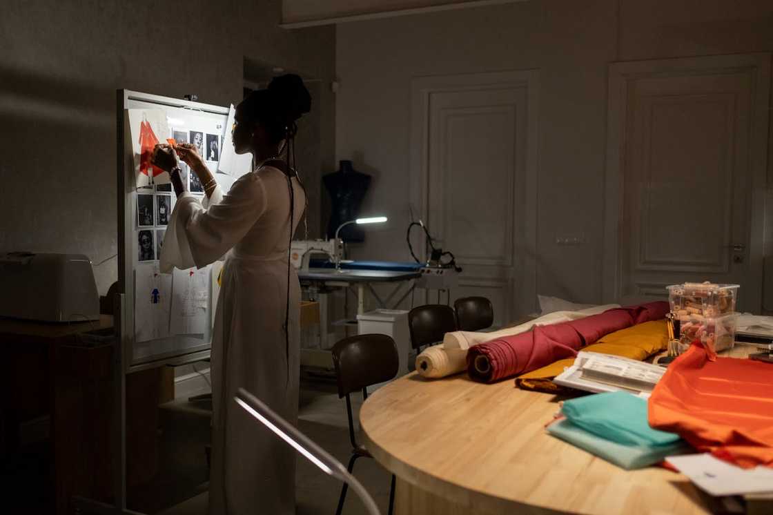 A designer pins sketches and fabric samples to a design board. A designer pins sketches and fabric samples to a design board.