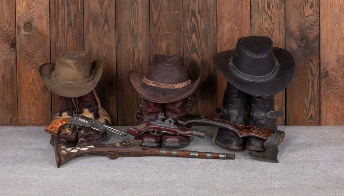 cowboy hat, boots and gun on a wooden floor cowboy hat, boots and gun on a wooden floor