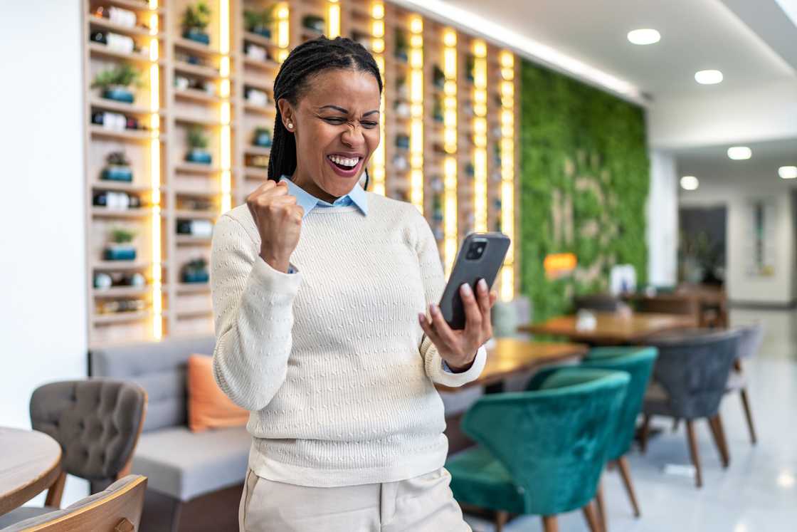 A lady happily smiles as she looks at her phone