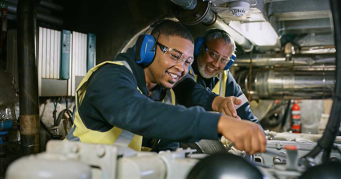 Senior expert mechanic coaching a young guy in a manufacturing plant