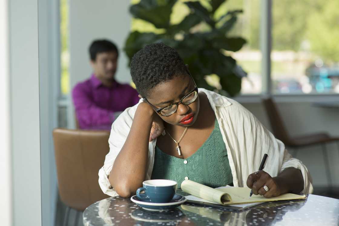 Young woman writes on notepad in a cafe Young woman writes on notepad in a cafe