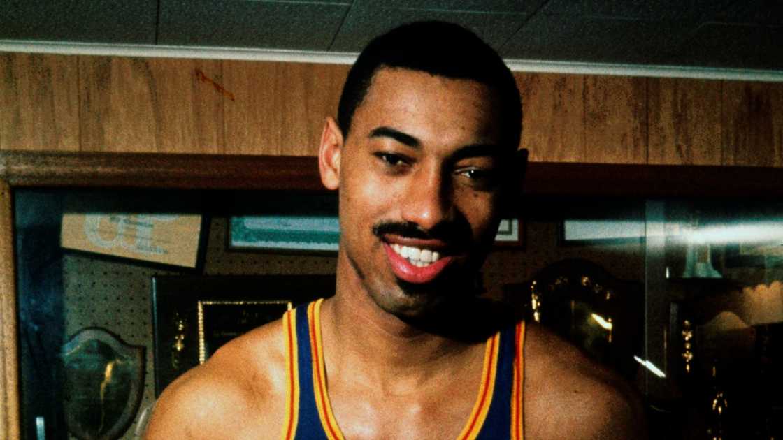 Philadelphia Warriors player Wilt Chamberlain poses while holding a basketball.