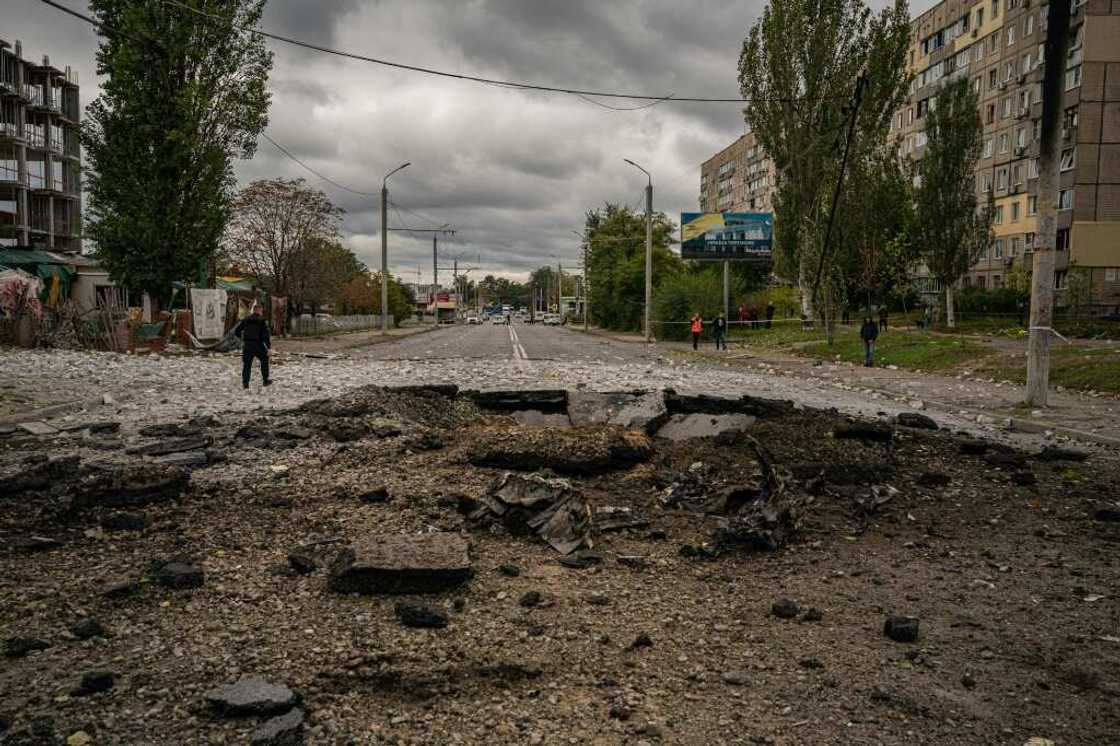 A policeman walks next to a crater following a missile strike in Dnipro A policeman walks next to a crater following a missile strike in Dnipro