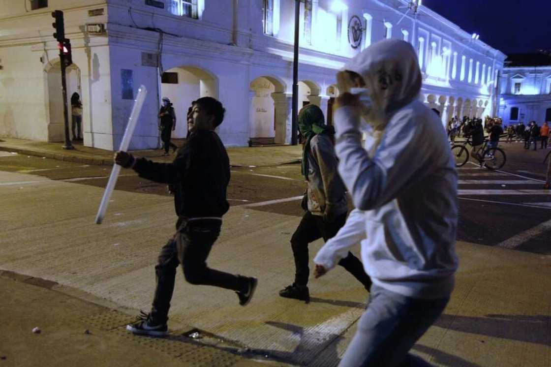 A demonstrator runs with a neon tube to throw at the police during Indigenous-led protests against the government in Ecuador A demonstrator runs with a neon tube to throw at the police during Indigenous-led protests against the government in Ecuador