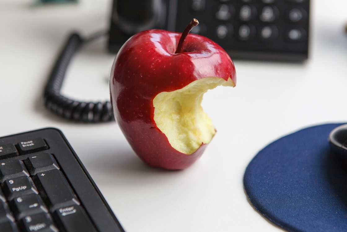 a half-eaten apple on office desk a half-eaten apple on office desk