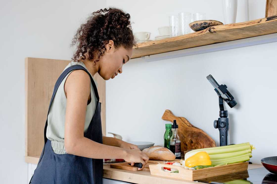 A young woman preparing food in a bright kitchen.