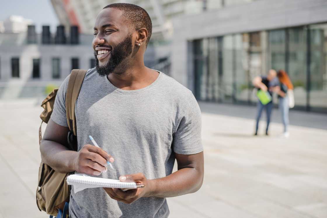 College students notes down something on his book