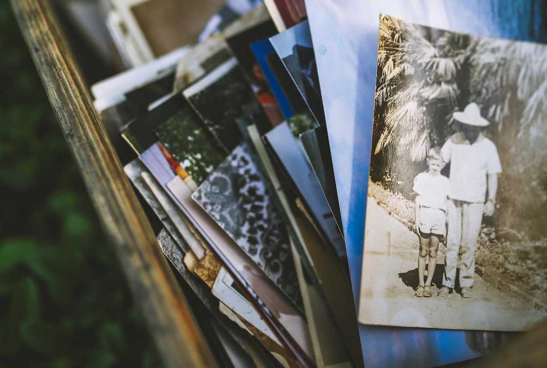 A stack of vintage family photos in a wooden box.