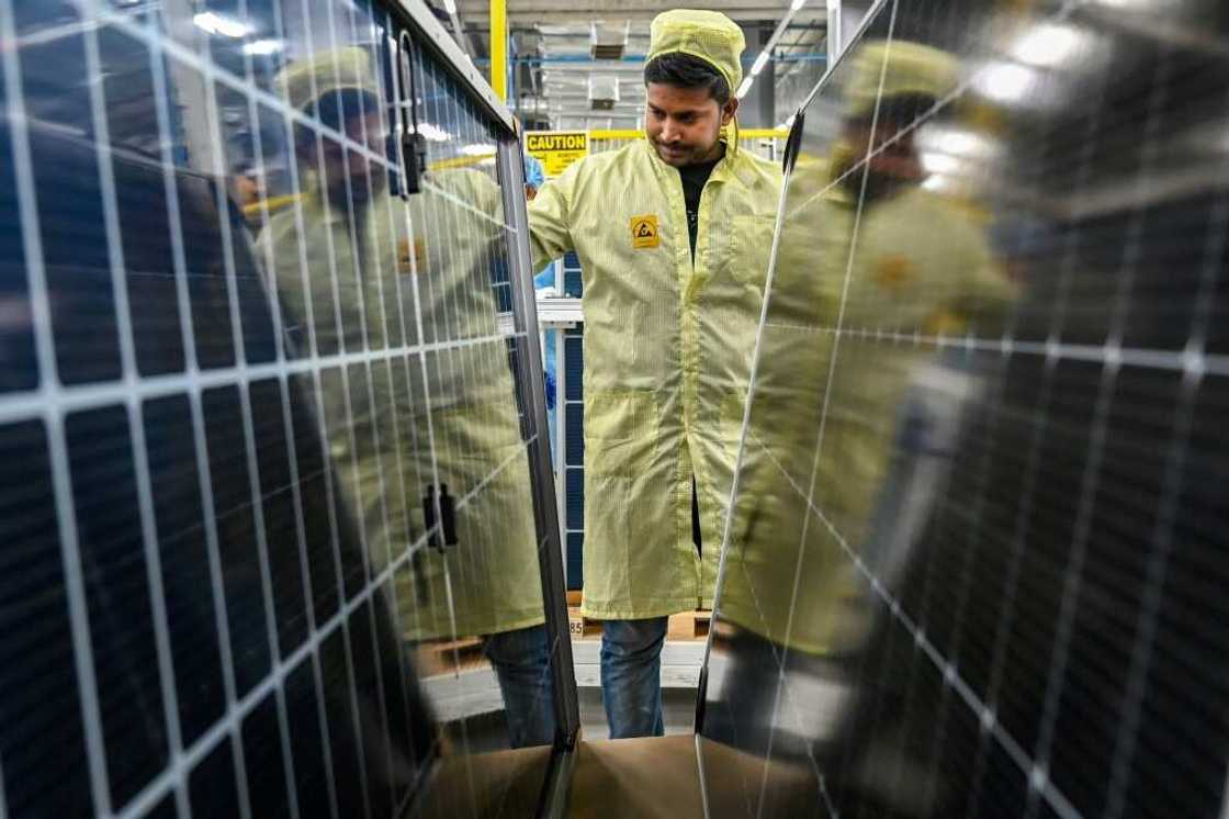 An employee inspects solar panels at an Adani Group factory in Mundra