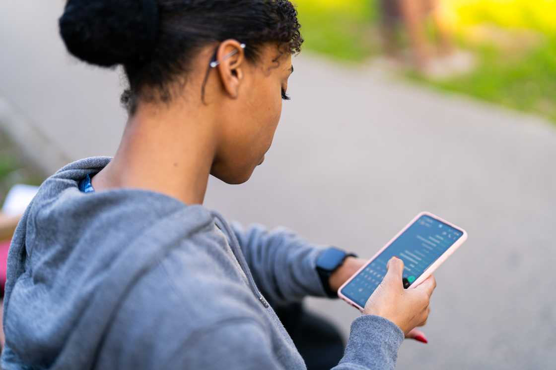 A person chats on her phone outdoors. A person chats on her phone outdoors.