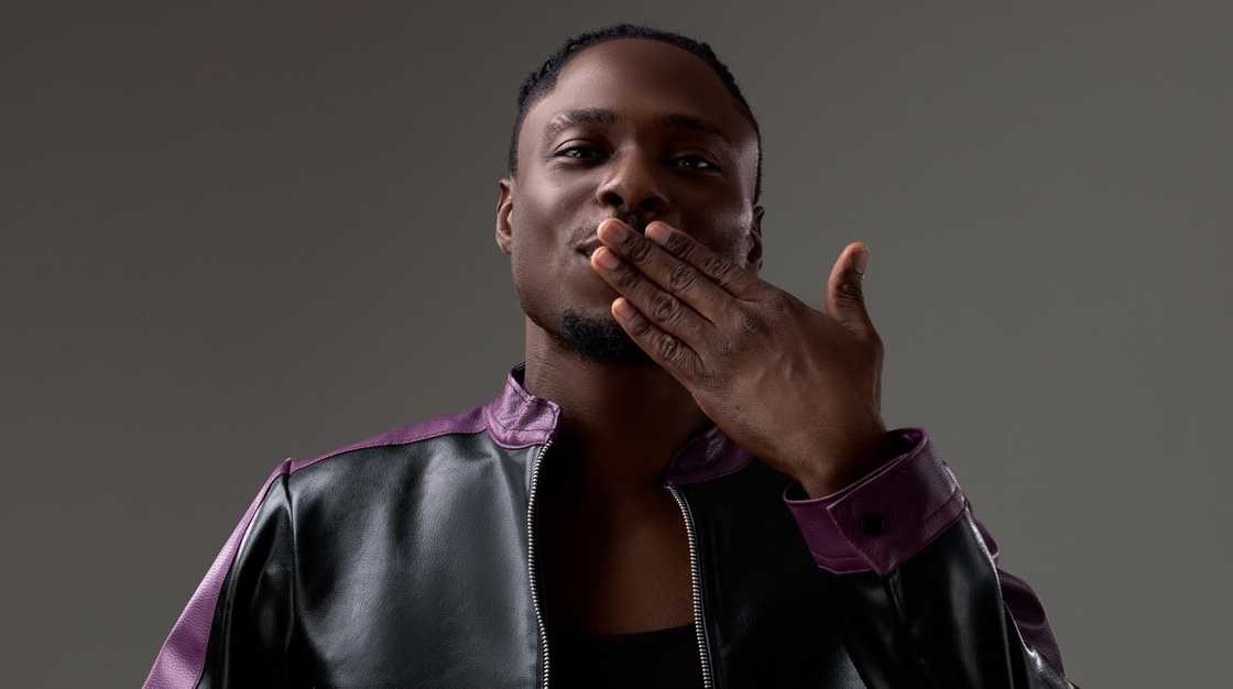 Faith from BBNaija blows a kiss during a photoshoot against a grey background.