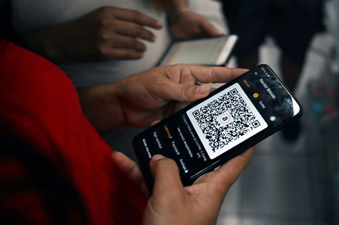 Two women make a transaction with a bitcoin app in Berlin, El Salvador