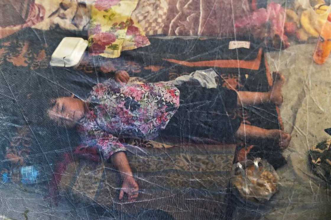 A displaced child sleeps under a mosquito net in a tent at a makeshift camp in Charsadda, Khyber Pakhtunkhwa