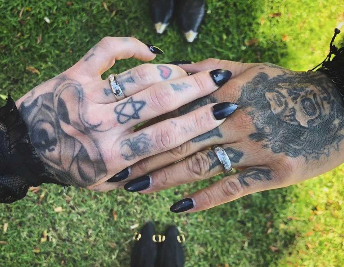 Kat Von D and Leafar Seyer hold hands with matching silver wedding bands and black manicures.