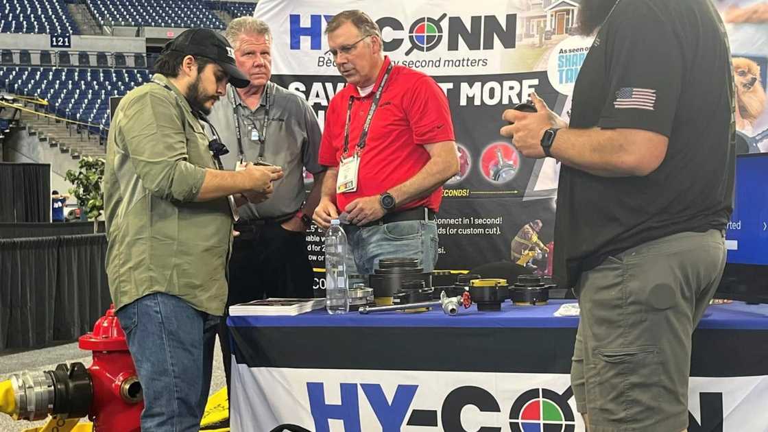 Jeff Stroope (C) demonstrates the Hy-Conn adapters to customers at the FDIC 2024