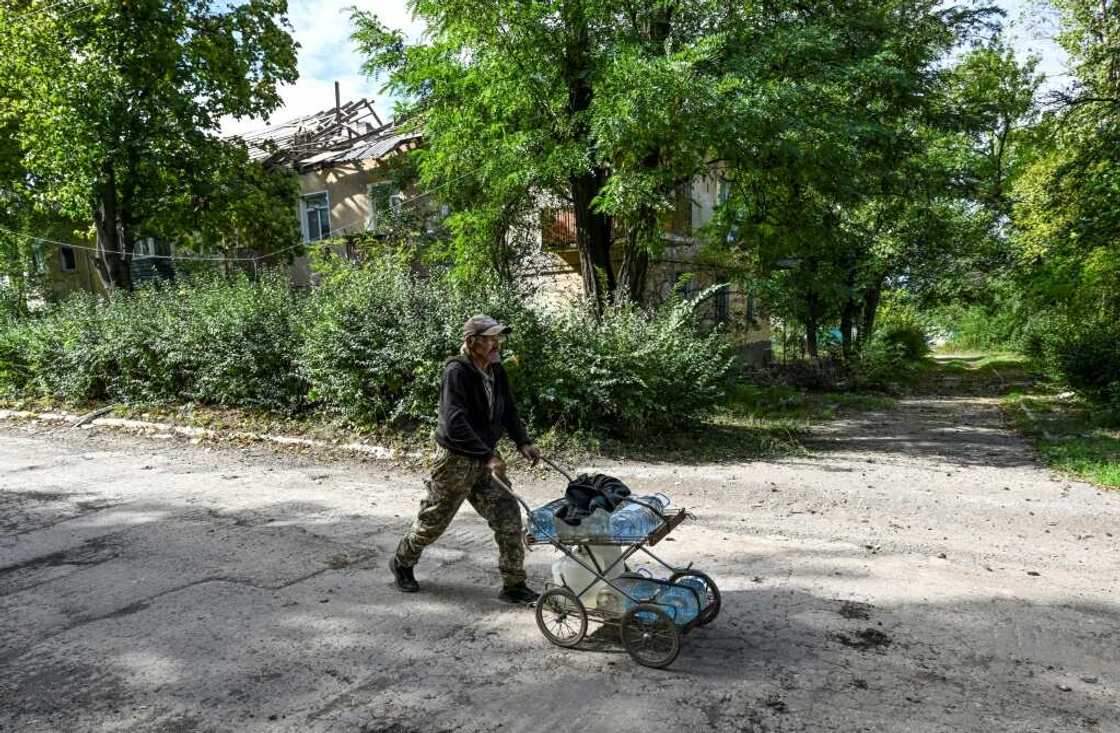 Sergiy Medvedev pushes water containers through the streets of Siversk in Ukraine's Donetsk region Sergiy Medvedev pushes water containers through the streets of Siversk in Ukraine's Donetsk region