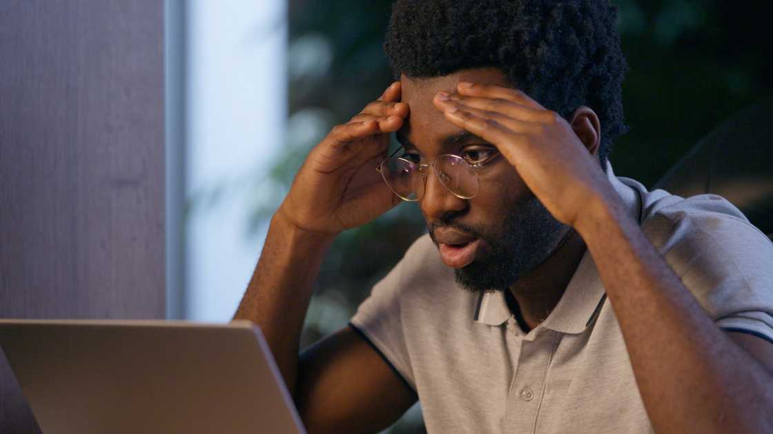 An upset young man using his laptop at night