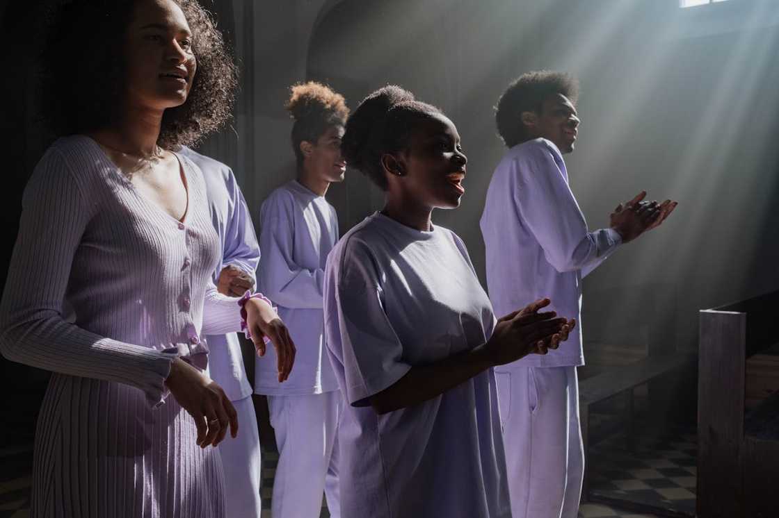 A group of people sing together inside a church with sunlight streaming in. A group of people sing together inside a church with sunlight streaming in.