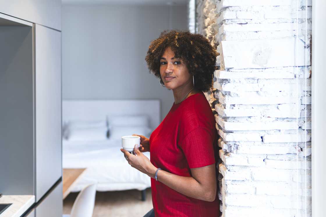 A woman poses in with a coffee cup.
