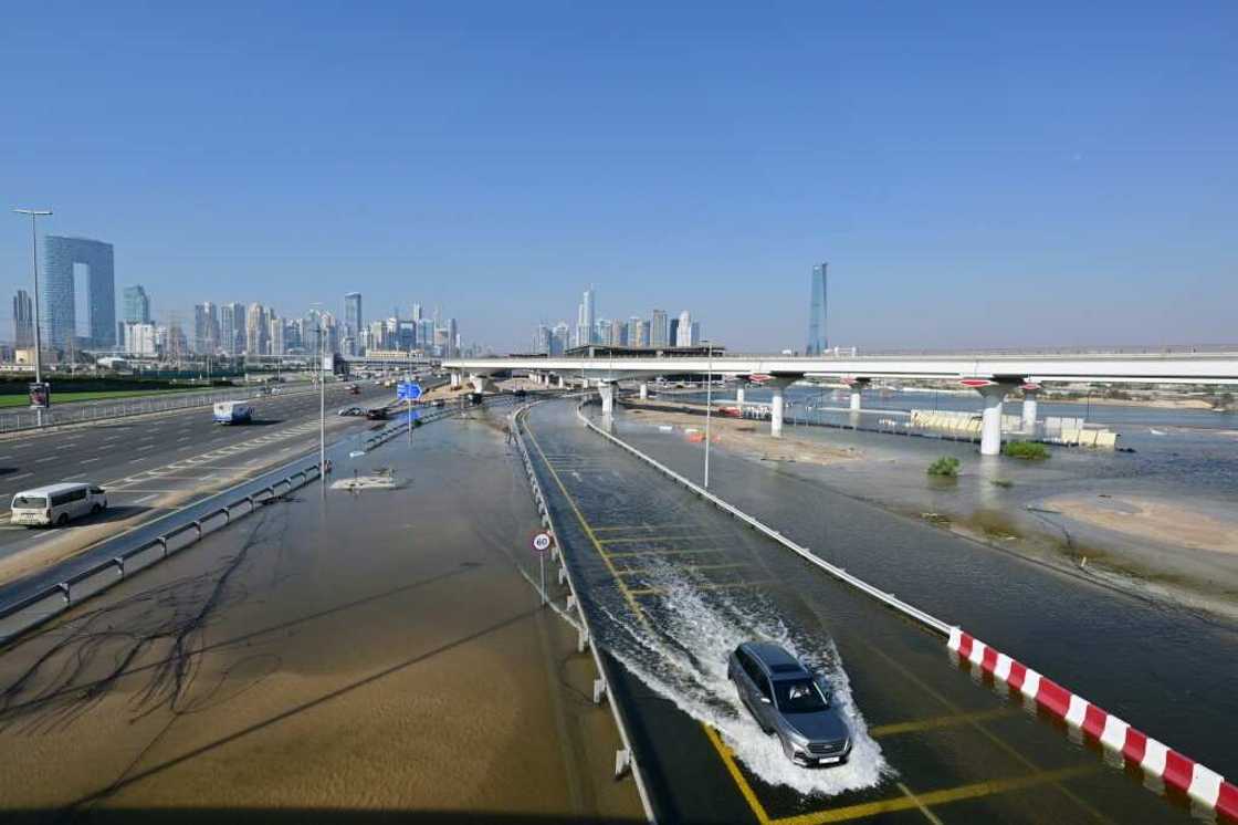 A car drives in a flooded road in Dubai on April 19, 2024. Floods have been tearing a path of destruction across the globe, hammering Kenya, submerging Dubai, and forcing hundreds of thousands of people from Russia to China, Brazil and Somalia from their homes.