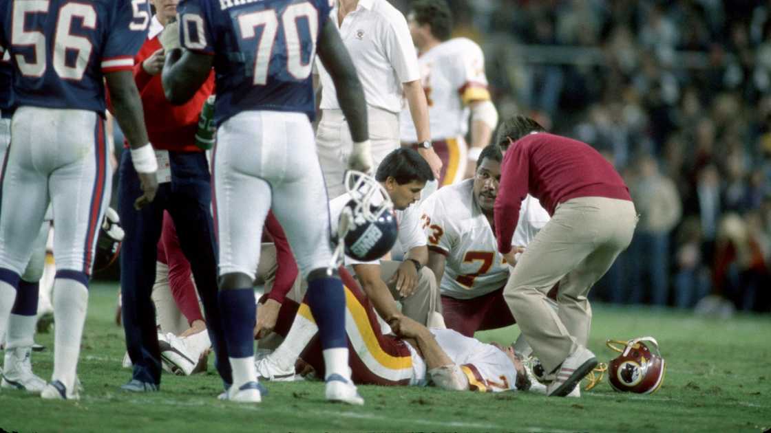 Washington Redskins quarterback Joe Theismann lies on the ground and is attended to by medical staff after an injury.