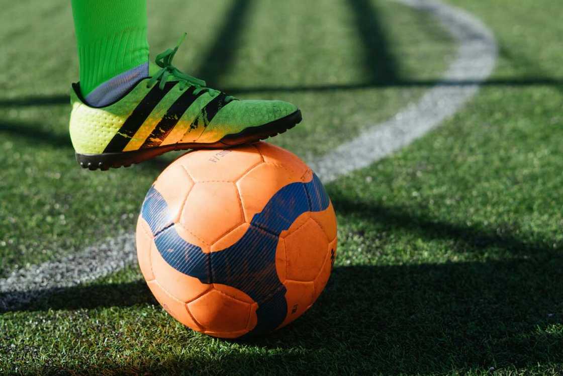 A person wearing neon green socks stepping on a ball on the ground