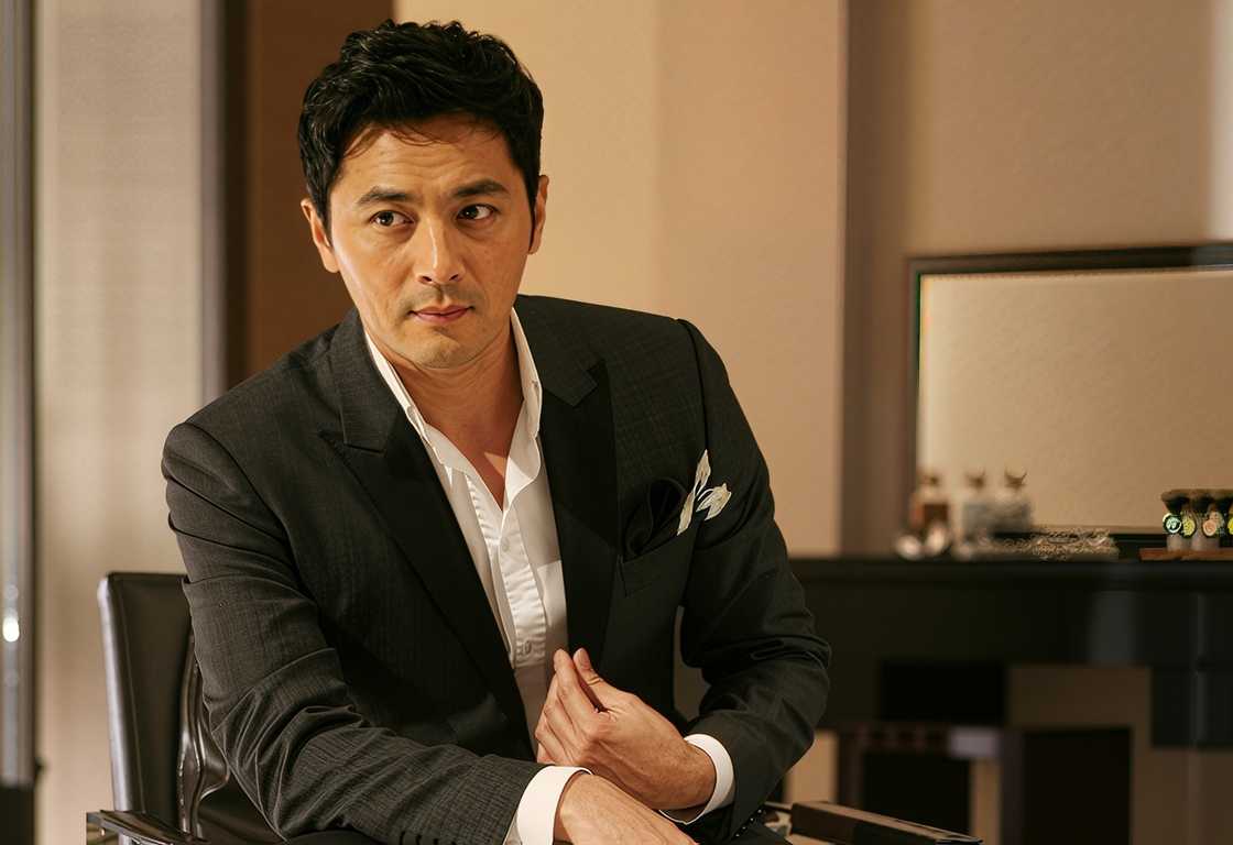 Jang Dong-gun sits indoors in a grey charcoal suit Jang Dong-gun sits indoors in a grey charcoal suit