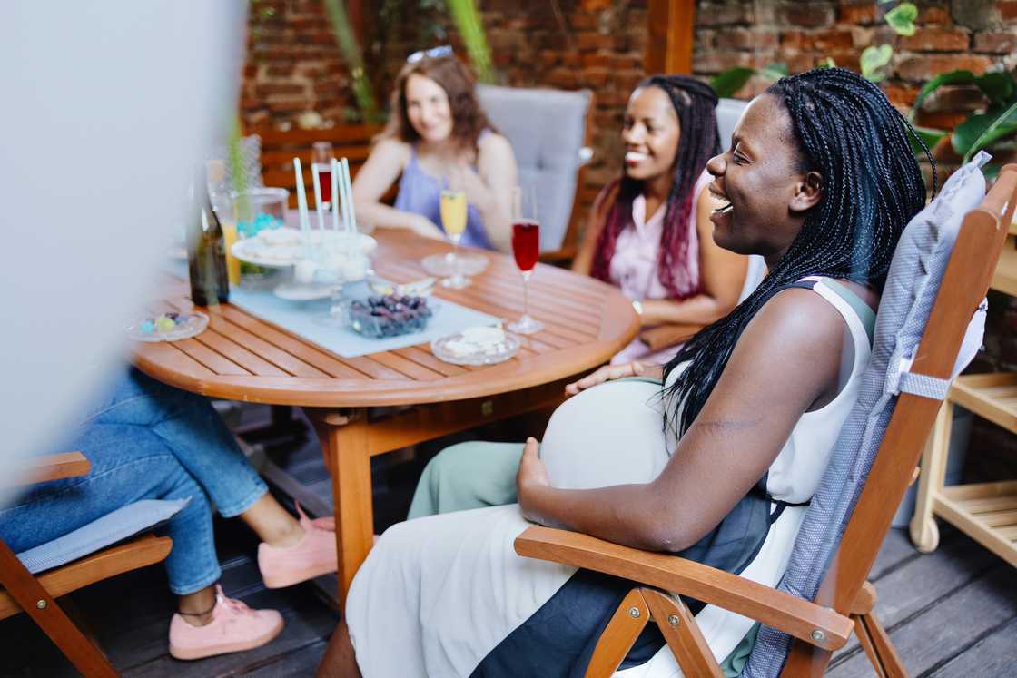 Smiling young pregnant woman celebrating baby shower with best friends Smiling young pregnant woman celebrating baby shower with best friends