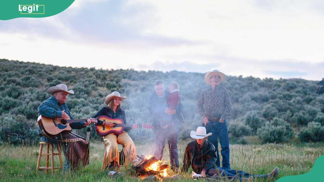 Family spending time together by outdoor campfire enjoying country music