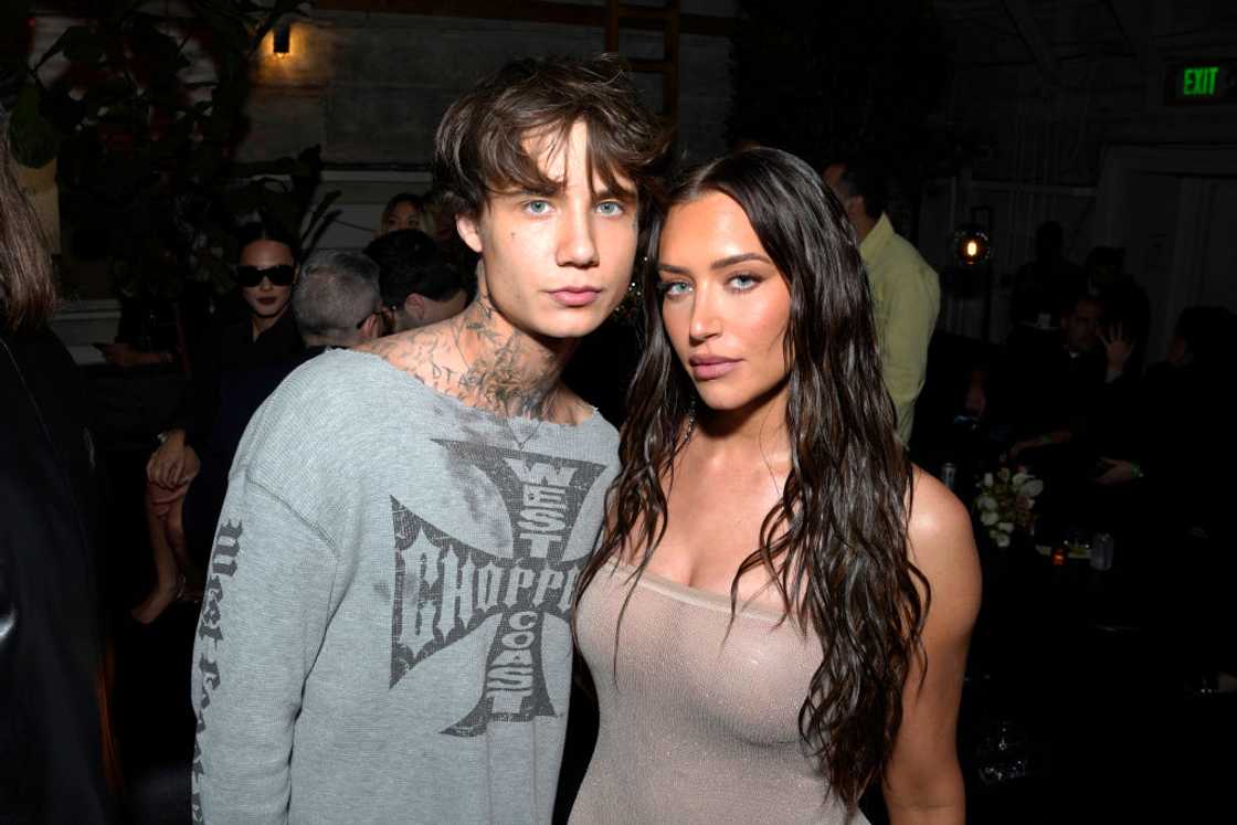 Jaden, (L) in a grey graphic sweater stands close with a brunette woman in a sheer beige top. Jaden, (L) in a grey graphic sweater stands close with a brunette woman in a sheer beige top.