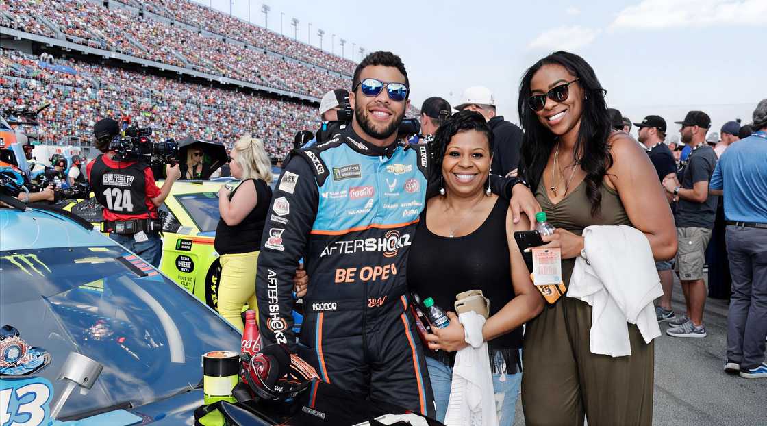 Bubba Wallace, his mother Desiree, and sister, Brittany, pose next to his car during a race event. Bubba Wallace, his mother Desiree, and sister, Brittany, pose next to his car during a race event.