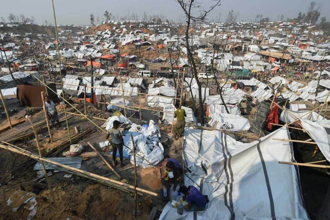 Rohingya refugee men build a temporary shelter days after a fire burnt their home at a refugee camp in Ukhia, in the southeastern Cox's Bazar district on March 25, 2021