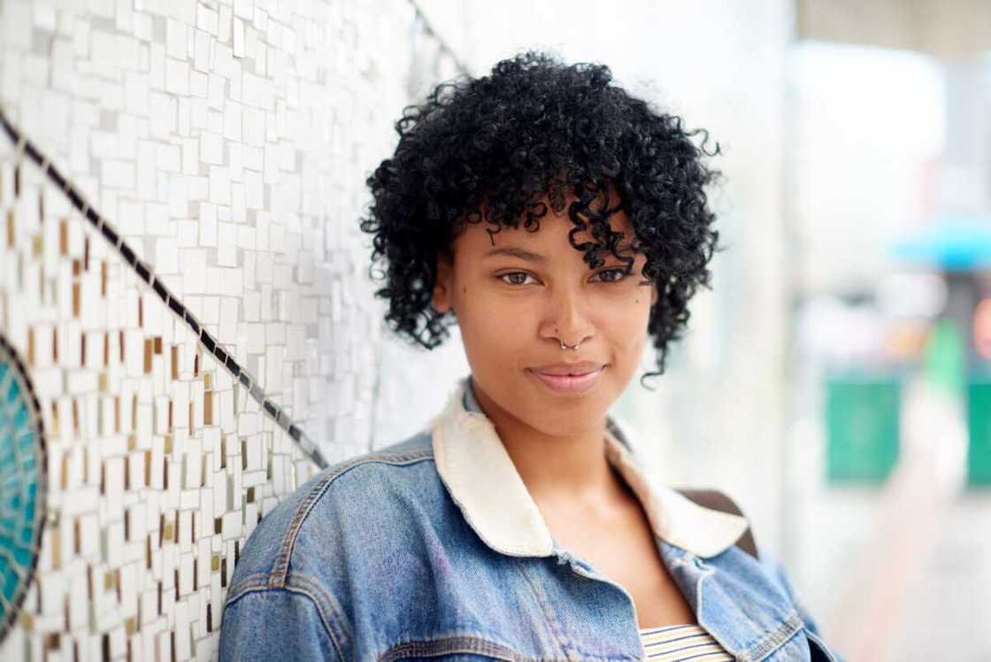 Portrait of a young woman standing against a colourful wall outdoors Portrait of a young woman standing against a colourful wall outdoors
