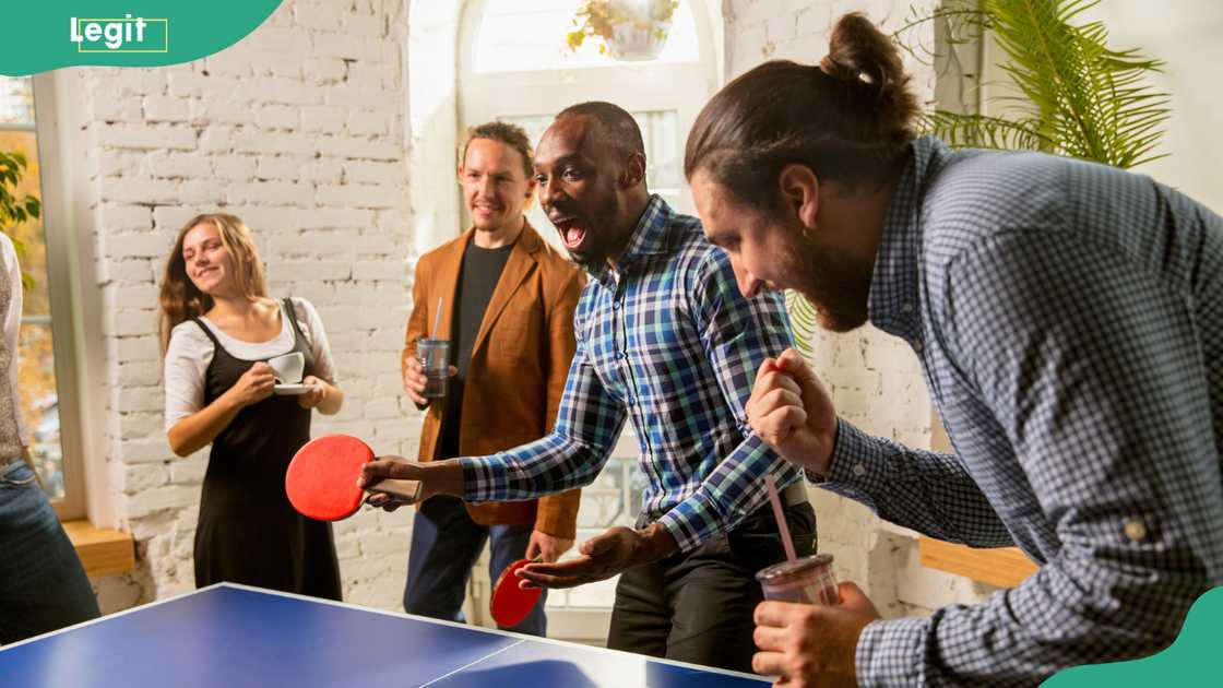 Young people having fun by playing table tennis in the workplace