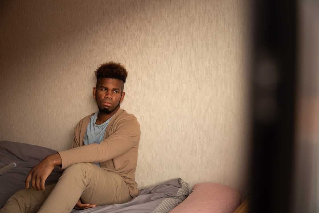 A young adult sitting alone on a bedroom floor. A young adult sitting alone on a bedroom floor.