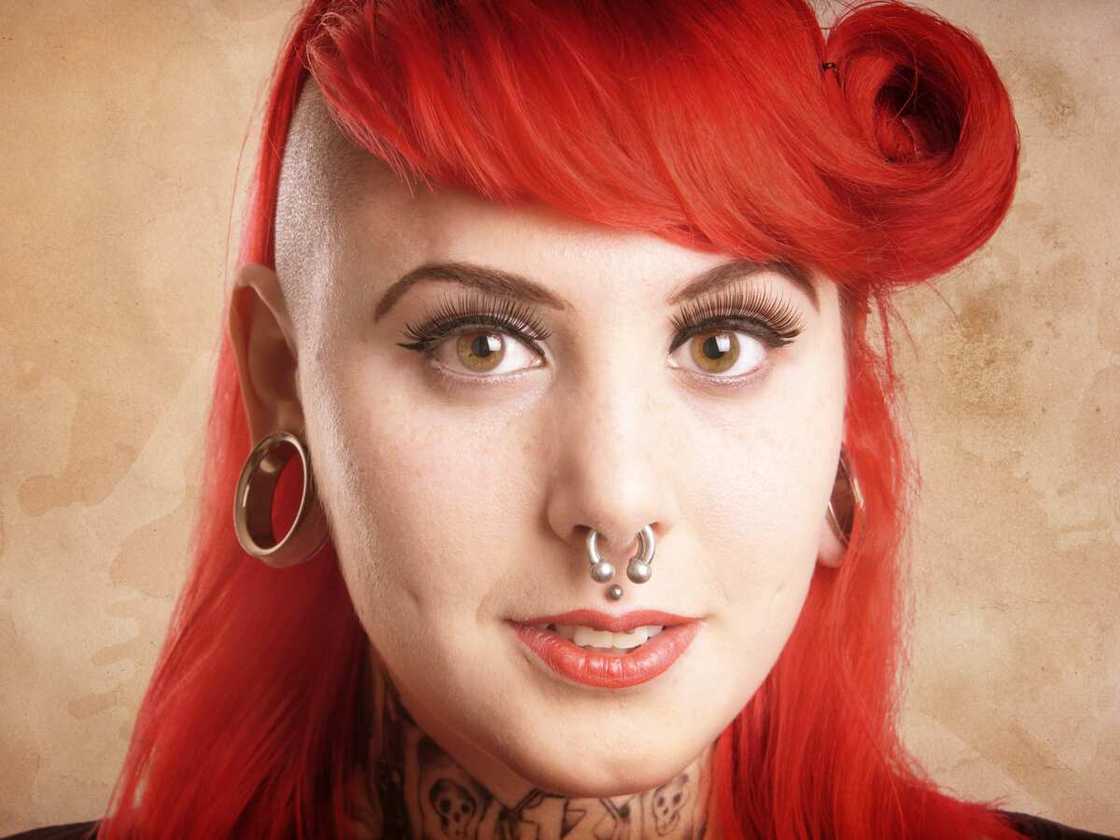 Young woman with side cut, facial piercings and tattoos - with added texture filter effect Young woman with side cut, facial piercings and tattoos - with added texture filter effect