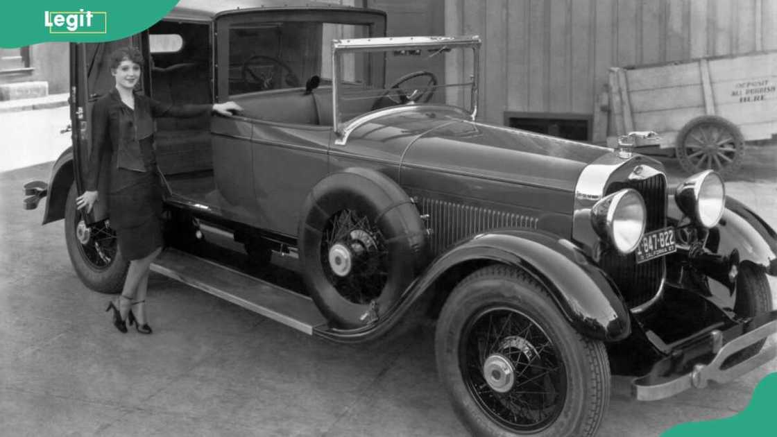 A young woman prepares to enter the rear compartment of a 1927 Lincoln L-series town car