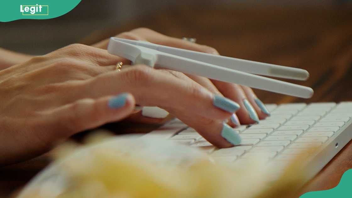 A person typing on a laptop while reaching for snacks from a Snactiv hands-free snack holder