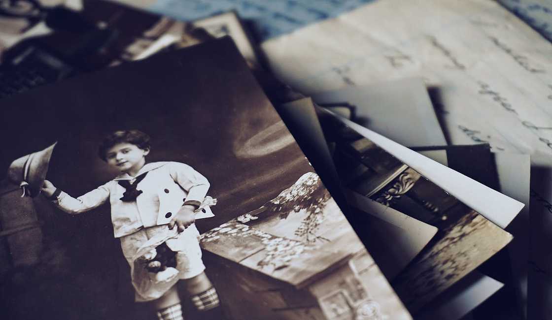 A pile of old photographs is scattered across a table. A pile of old photographs is scattered across a table.