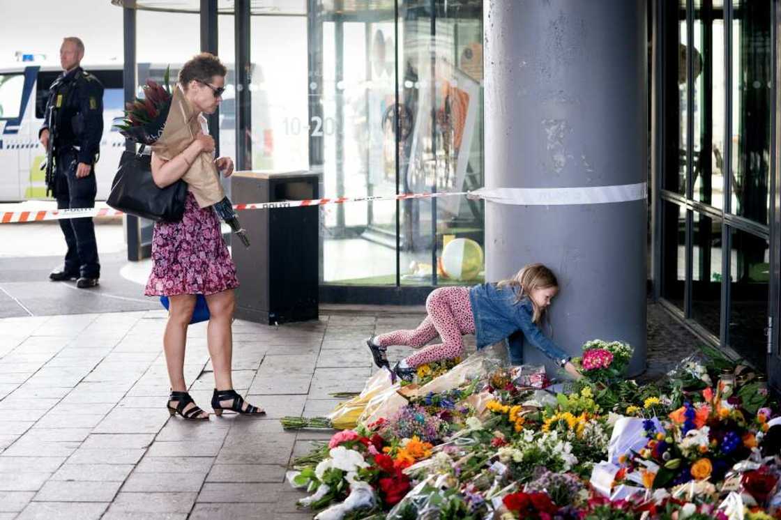 A girl places flowers at a makeshift memorial to the victims of the shooting in front of the Field's shopping centre