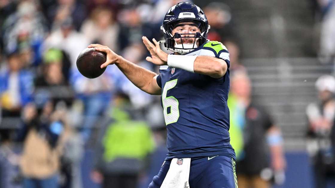 Sam Howell prepares to throw a ball on a football field.