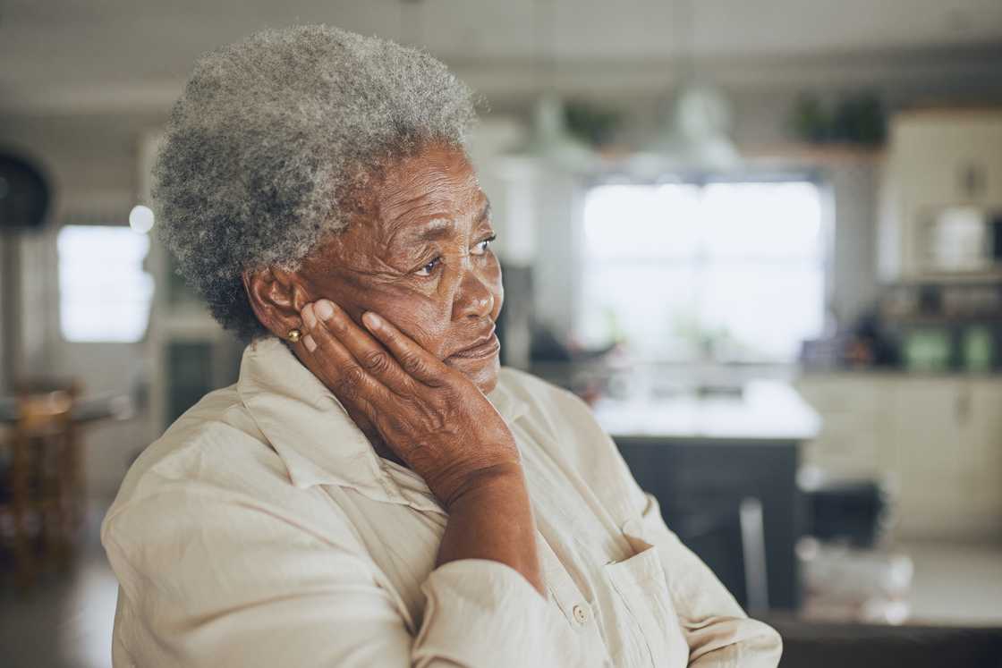 An elderly woman holds herself in a sad manner.
