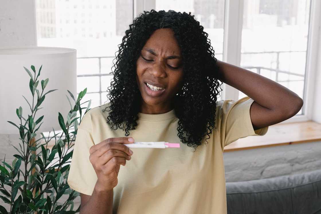 A woman stares at a pregnancy test in shock.