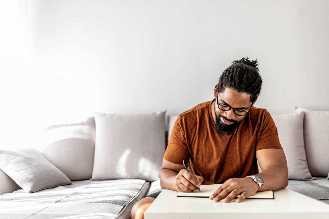 A man with a journal and pen sitting on the sofa A man with a journal and pen sitting on the sofa