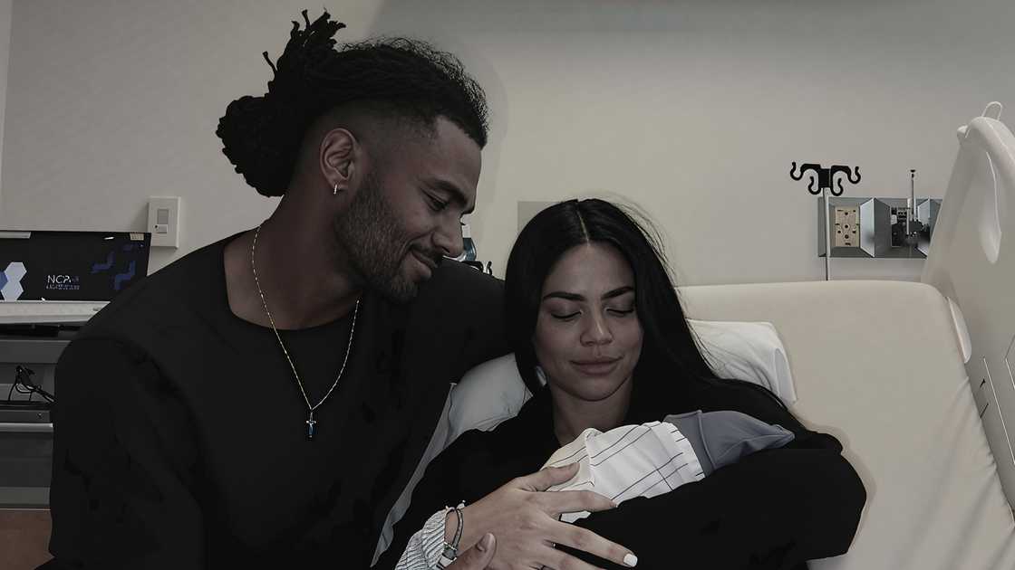 Fred Warner (L) and his wife, Sydney Hightower (R), hold their newborn child on a hospital bed.