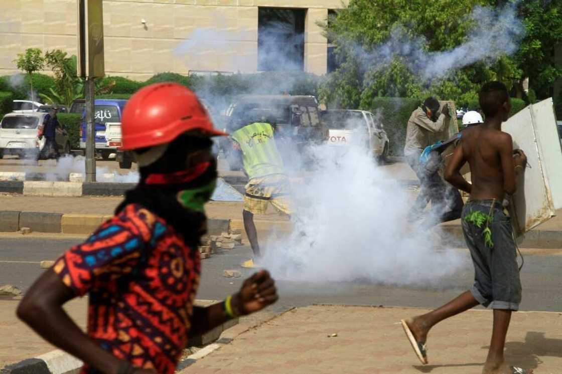 Youths run from tear gas fired by security forces as they protest in south Khartoum on August 31, 2022, to demand the return of civilian rule