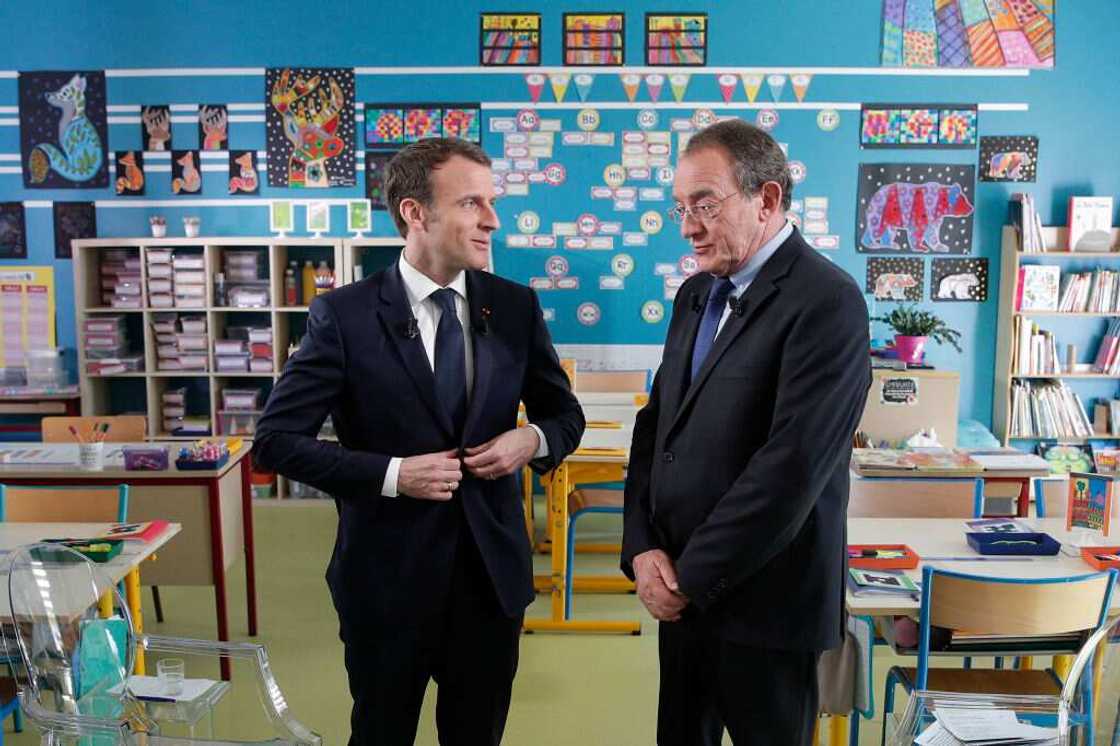 Le président français Emmanuel Macron (à gauche) s'entretient avec le journaliste français Jean-Pierre Pernaut (à droite) après avoir été interviewé à l'intérieur de la salle de classe sur la chaîne de télévision française TF1 à l'école de Berdhuis.